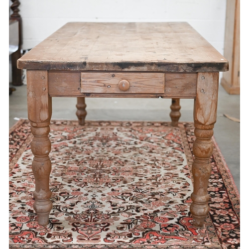 68 - A rustic waxed pine farmhouse dining table with drawer to one end, raised on turned legs, 182 cm x 9... 