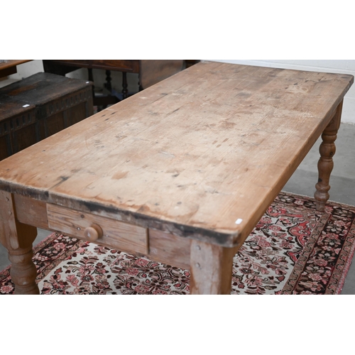 68 - A rustic waxed pine farmhouse dining table with drawer to one end, raised on turned legs, 182 cm x 9... 