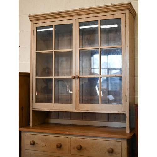 69 - A vintage pine dresser with glazed doors enclosing two shelves, on a cabinet base with two drawers o... 