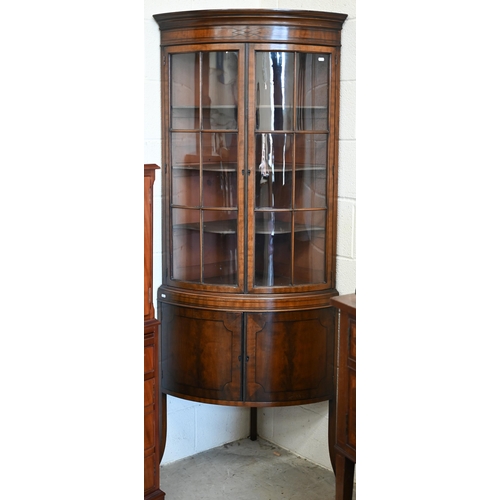 71 - An Edwardian mahogany barrel-front corner cabinet with glazed doors enclosing shelves on cabinet bas... 