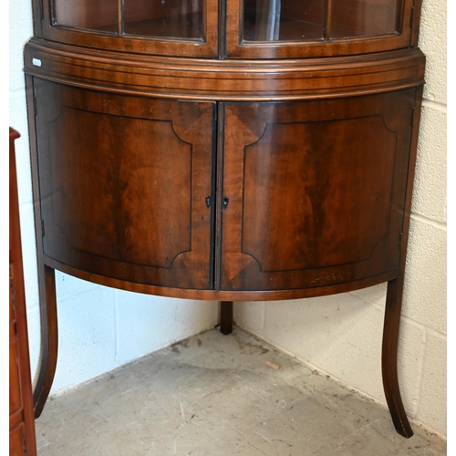 71 - An Edwardian mahogany barrel-front corner cabinet with glazed doors enclosing shelves on cabinet bas... 