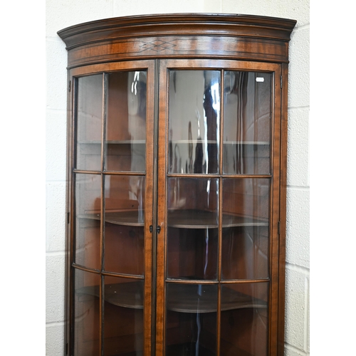 71 - An Edwardian mahogany barrel-front corner cabinet with glazed doors enclosing shelves on cabinet bas... 