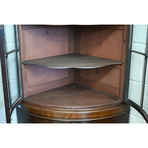 71 - An Edwardian mahogany barrel-front corner cabinet with glazed doors enclosing shelves on cabinet bas... 