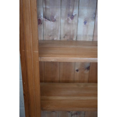 77 - A stained pine open bookcase with moulded cornice and five fixed shelves, 142 cm w x 30 cm d x 186 c... 