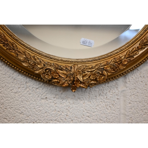 78 - A pair of bevelled oval wall mirrors in decorative laurel design giltwood and gesso frames, 44 cm w ... 