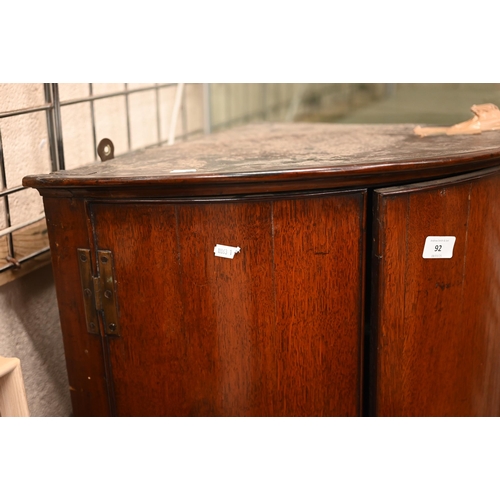 92 - A Georgian oak barrel-front corner cupboard with two doors enclosing shelved interior, 84 cm h