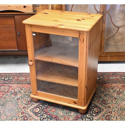 134 - A stained pine media cabinet with glazed door and bun feet, 58 x 44 x 80 cm high to/w two drawer fil... 