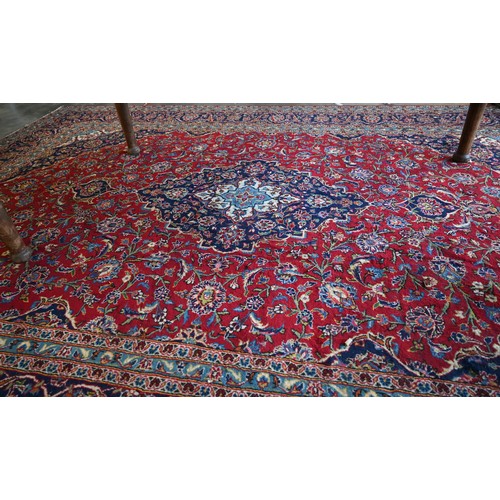 295 - Large Central Persian Kashan carpet, traditional floral design on red ground within conforming blue ... 