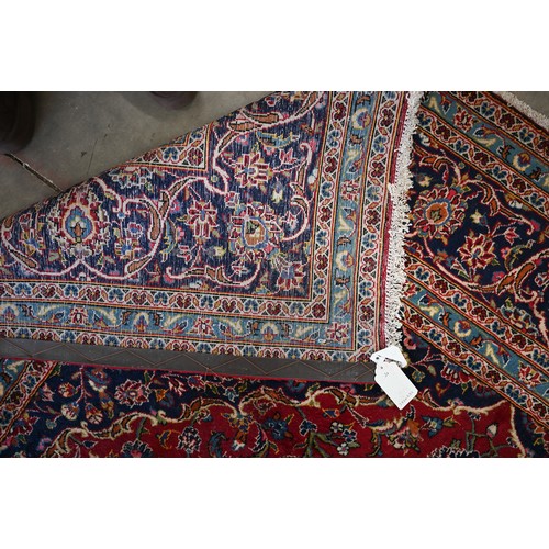 295 - Large Central Persian Kashan carpet, traditional floral design on red ground within conforming blue ... 