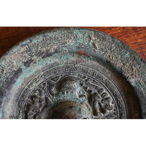 470 - A Japanese bronze circular mirror of traditional form, embossed with dragons, 12.5 cm diameter