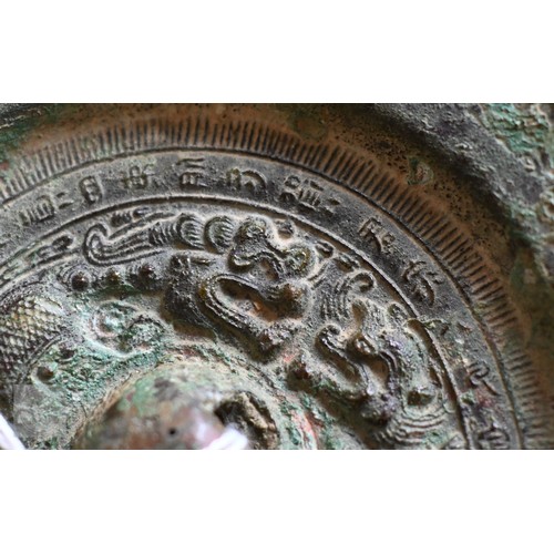 470 - A Japanese bronze circular mirror of traditional form, embossed with dragons, 12.5 cm diameter