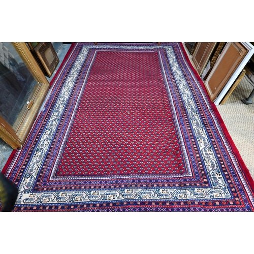 636 - A North West Persian Arak carpet, the repeating floral design on red ground, 315 cm x 215 cm