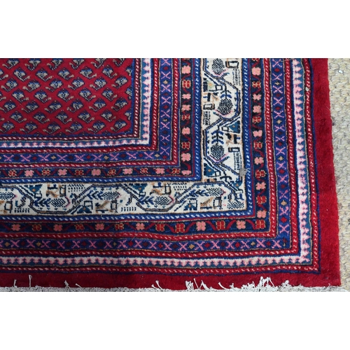636 - A North West Persian Arak carpet, the repeating floral design on red ground, 315 cm x 215 cm