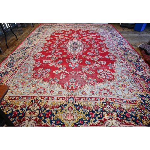 656 - A large Persian Kerman red ground carpet with traditional floral design around the central medallion... 