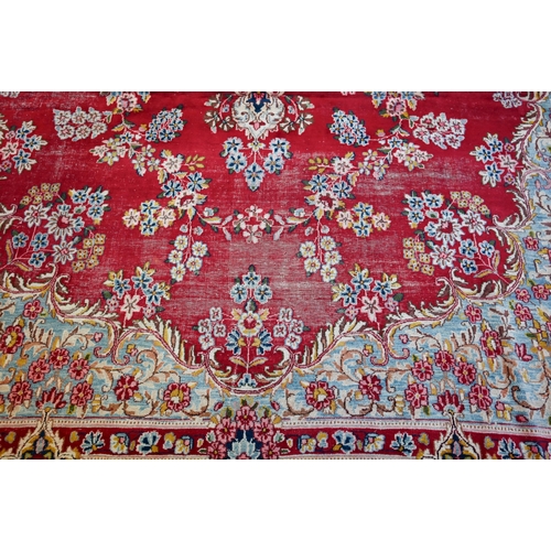 656 - A large Persian Kerman red ground carpet with traditional floral design around the central medallion... 