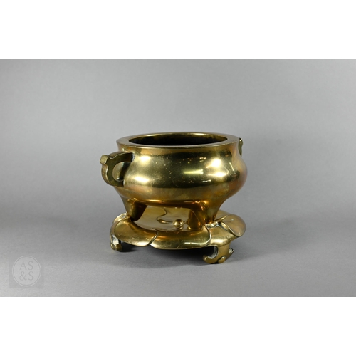 An 18th century Chinese polished bronze censer (incense burner) and stand, the censer with compressed globular body and loop handles standing on three conical feet, the base cast with an apocryphal four character Xuande seal mark, resting on a naturalistic lotus leaf design stand, Qing Dynasty, 