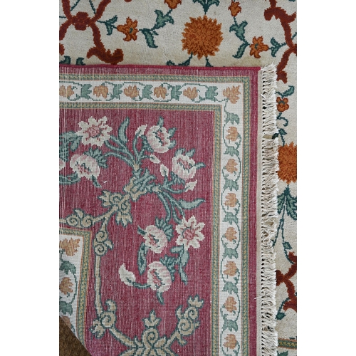 643 - An Indo-Persian Agra carpet with floral herati design on camel ground with red floral scroll border,... 