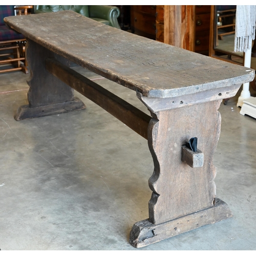 A 17th/18th century oak refectory table, the single plank top raised on shaped trestle ends united by a mid-height pegged stretcher, the surface finish heavily worn and patinated by age, odd bit of evidence of old worm, corners later canted, no pegs present, 215 cm x 54 cm x 77 cm h