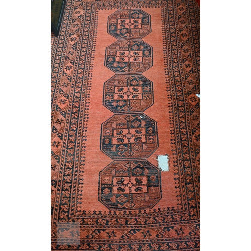 591 - An old Afghan rug with five medallions on pale red ground, 209 x 120 cm