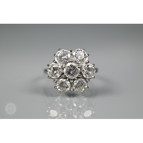 A large diamond cluster ring in the form of a daisy with central diamond and six diamonds around, white metal set stamped 18ct, size O 1/2, approx 3.0 carats diamond weight