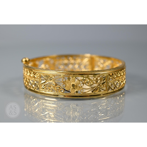 147 - A yellow metal bangle of decorative pierced form, probably Indian, with concealed screw fastener, 6 ...