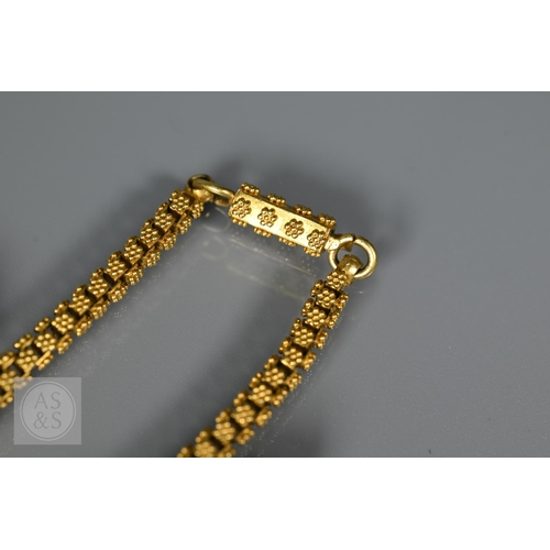 184 - An Indian fringe necklace of yellow metal chain with granulated links, suspending forty green, red a... 