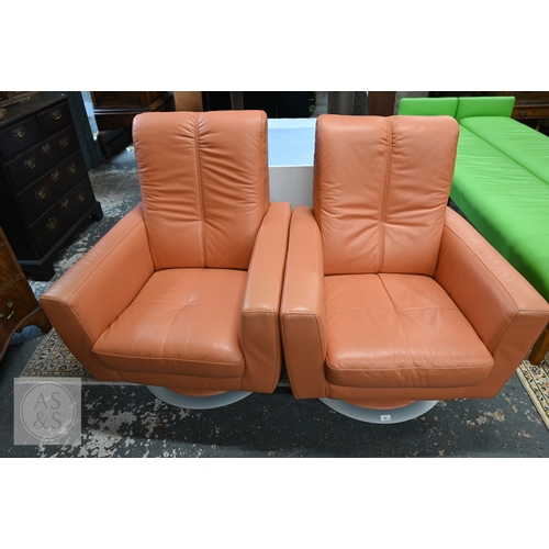 381 - A pair of mid-century modern style swivel chairs in peach leather upholstery, circular brushed alumi... 