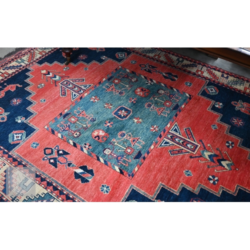 42 - An Afghan Caucasian/Kazak design rug, figural central medallion on red ground, dark blue spandrels w... 