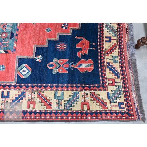 42 - An Afghan Caucasian/Kazak design rug, figural central medallion on red ground, dark blue spandrels w... 
