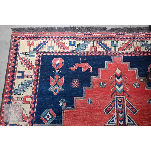 42 - An Afghan Caucasian/Kazak design rug, figural central medallion on red ground, dark blue spandrels w... 
