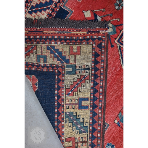 42 - An Afghan Caucasian/Kazak design rug, figural central medallion on red ground, dark blue spandrels w... 