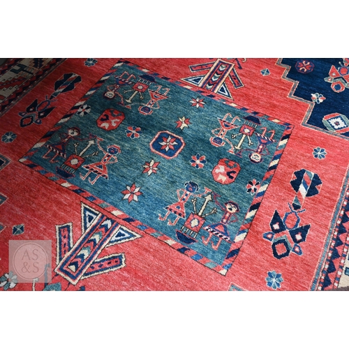 42 - An Afghan Caucasian/Kazak design rug, figural central medallion on red ground, dark blue spandrels w... 