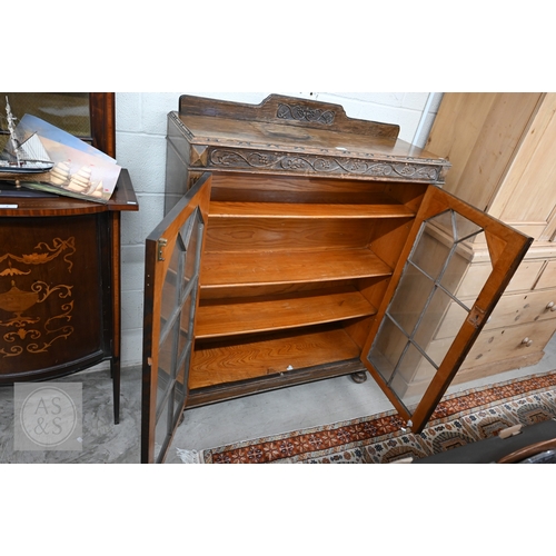 9 - A mid 20th century carved oak bookcase, two glazed doors enclosing adjustable shelving standing on t... 