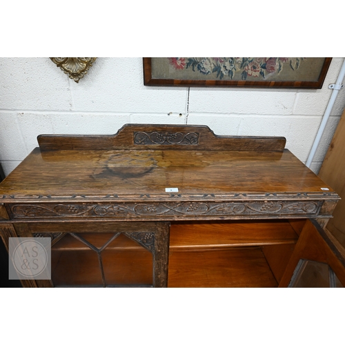 9 - A mid 20th century carved oak bookcase, two glazed doors enclosing adjustable shelving standing on t... 