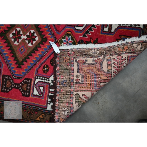 45 - A Persian Hamadan rug, of lozenge medallion design on red ground, with brown palmette and leaf borde... 