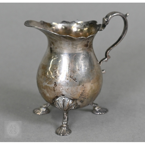 23 - A heavy quality silver pear-shaped cream jug in the Georgian manner, with scroll handle and shell fe... 