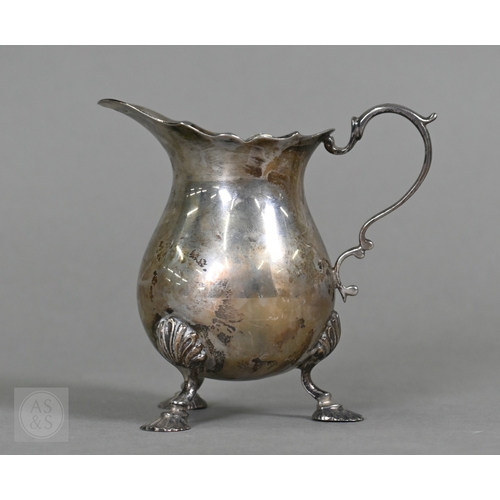 23 - A heavy quality silver pear-shaped cream jug in the Georgian manner, with scroll handle and shell fe... 