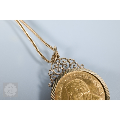 350 - A 1974 South African Krugerrand in 9ct yellow gold mount with scroll top, 38.6g all in, on yellow me... 