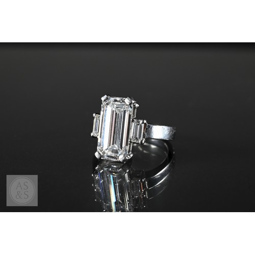 An exceptional diamond ring, the cut-cornered step-cut diamond with baguette cut diamonds to each shoulder, claw set to white metal mount and simple shank, size J, c/w certificate 