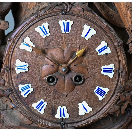 810 - J Huggler (1834-1912) a monumental carved Black Forest clock, late 19th century, carved as a seated ... 