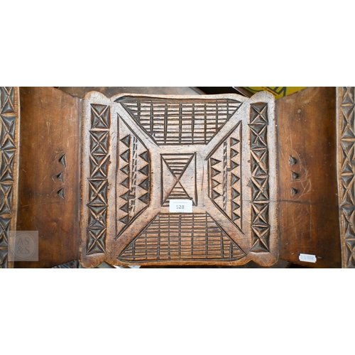 528 - An African carved wood stool with geometric patterned decoration, 39 x 53 cm, to/w a painted fibre p... 