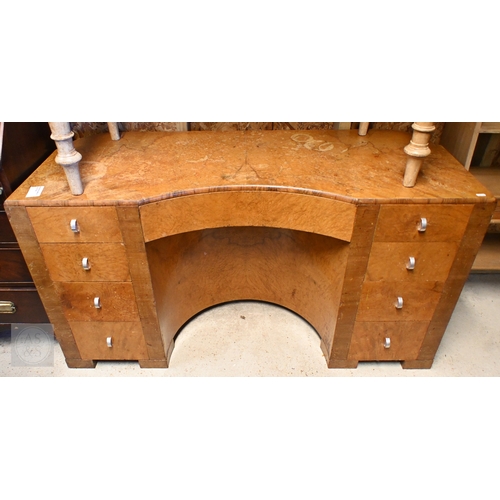 56 - An Art Deco walnut dressing table, centred by a concave recess with frieze drawers flanked by four d... 