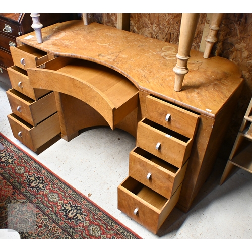 56 - An Art Deco walnut dressing table, centred by a concave recess with frieze drawers flanked by four d... 
