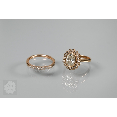A contemporary 18ct rose gold diamond cluster ring, the oval bezel set diamond with sixteen diamonds around, 1.5 x 1.1 cm overall, size L, diamond approx 1.2 carats to/w matching half diamond set band size L 1/2 (2)