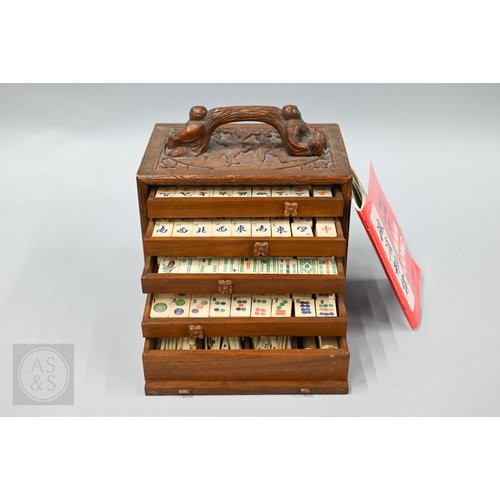 312 - An early-mid 20th century Chinese Mah Jong set, the wooden case decoratively carved with landscapes ... 