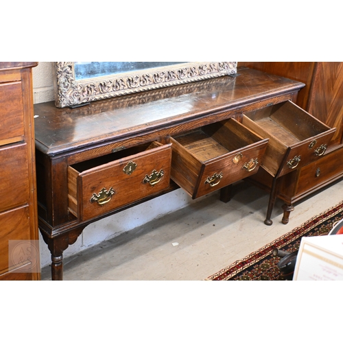213 - A George III oak low dresser, three drawers with traditional brass handles raised on turned supports... 