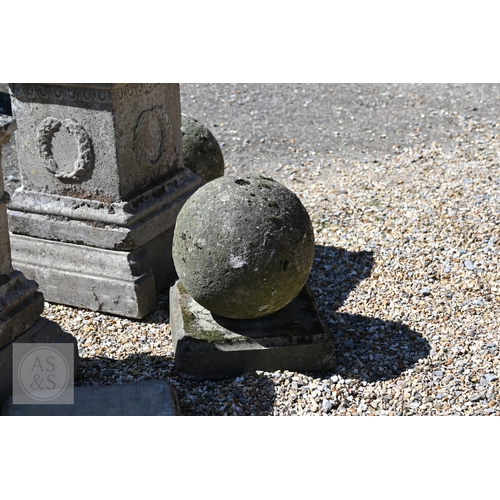 4 - A pair of old weathered cast stone ball finials raised on square cast stone plinths, 89 cm h  to/wit... 