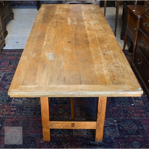 34 - A large oak refectory dining table, the framed wide plank top raised on square supports united by a ... 