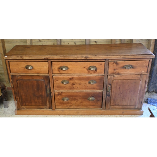42 - An old stained pine low dresser centred by three short drawers flanked by a drawer over cupboard to ... 