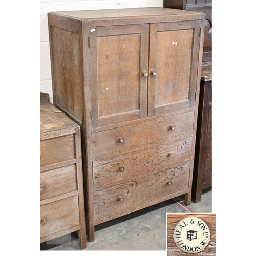 70 - Heal & Son, London - a limed oak cabinet with panelled cupboards over three drawers, ivorine pla... 